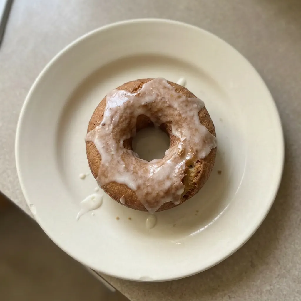 A serving of two small donuts, one topped with powdered sugar and the other with cinnamon sugar, on a plate.