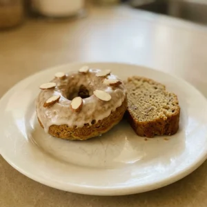 Overhead shot of two banana bread donuts with sliced almonds and cinnamon on top.