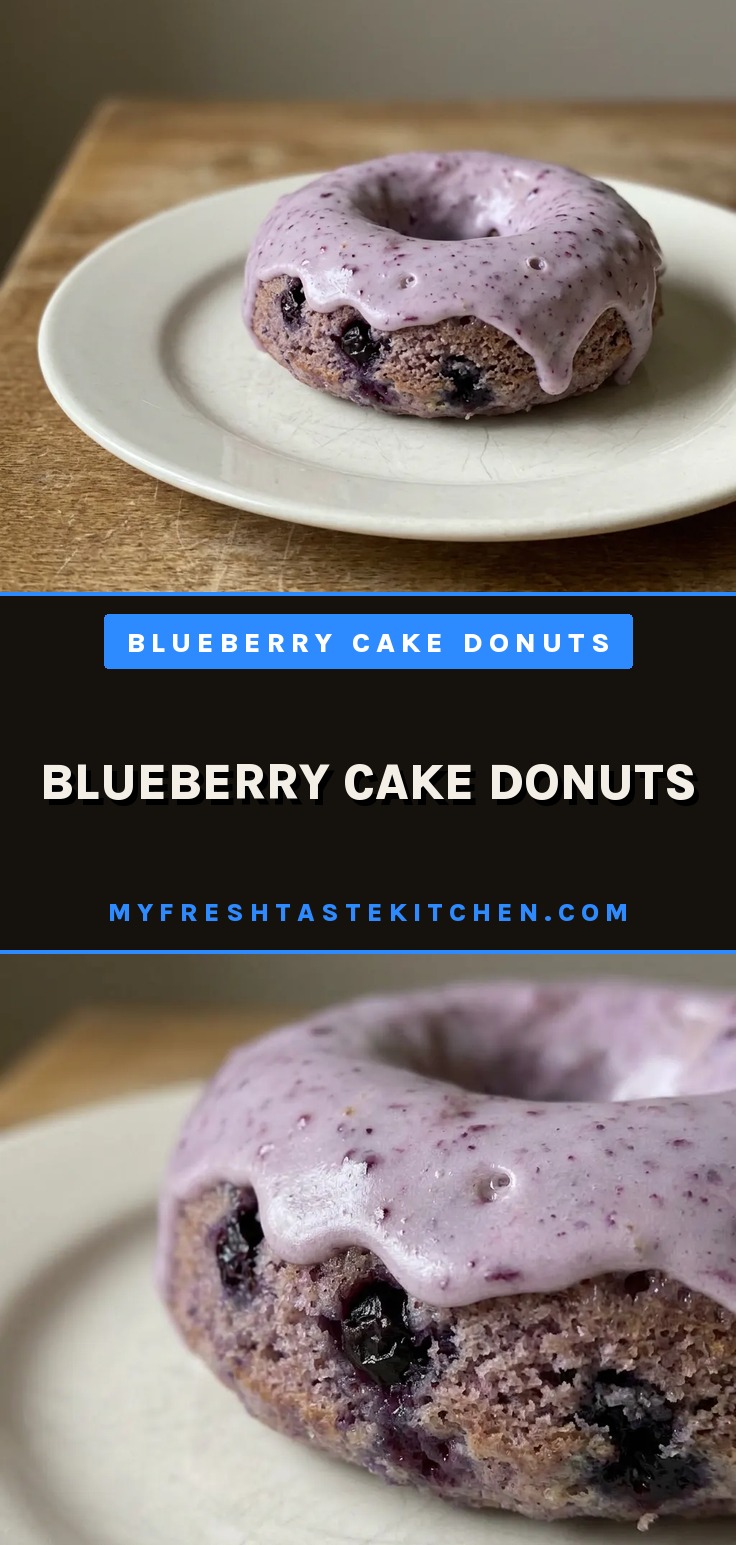 Blueberry cake donuts with glossy purple glaze and visible wild blueberries on a white surface.