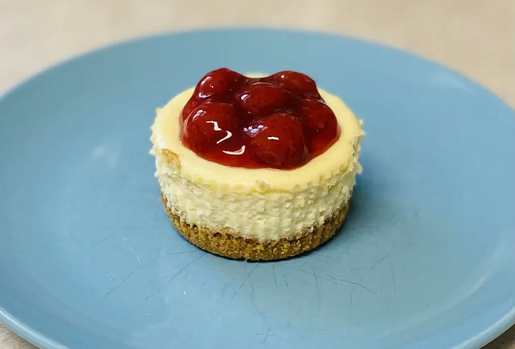 Looking down at three cheesecake cupcakes topped with strawberry slices and graham cracker crumbs.