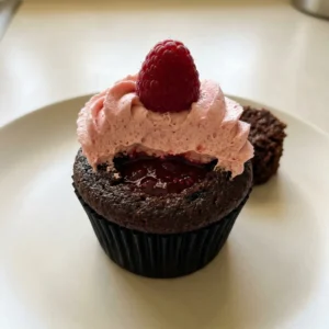 Top-down look at three chocolate cupcakes topped with swirls of raspberry buttercream and a fresh raspberry on each.
