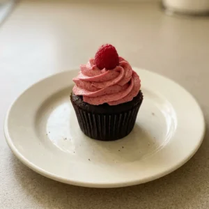 Overhead shot of a chocolate cupcake topped with raspberry buttercream and a freeze-dried raspberry.