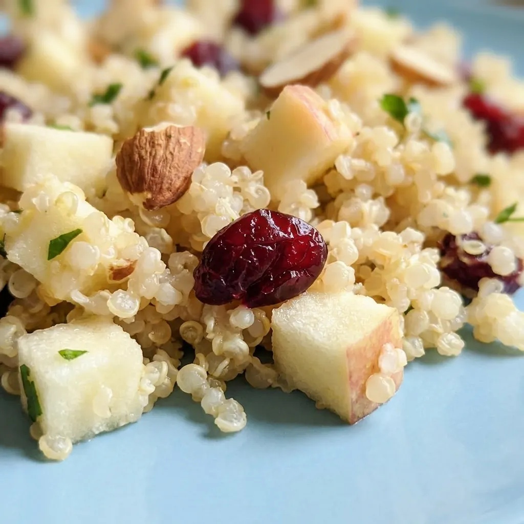 Zoomed in on a forkful of quinoa salad with visible apple cubes, cranberries, parsley leaves, and almond slivers.