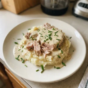 Top-down look at two pork chops in creamy sauce with visible ranch seasoning specks and melted butter pools.