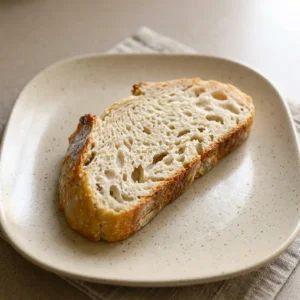 Bird's-eye view of a round loaf with a golden brown crust and a dusting of coarse salt, sliced into wedges revealing an airy crumb.