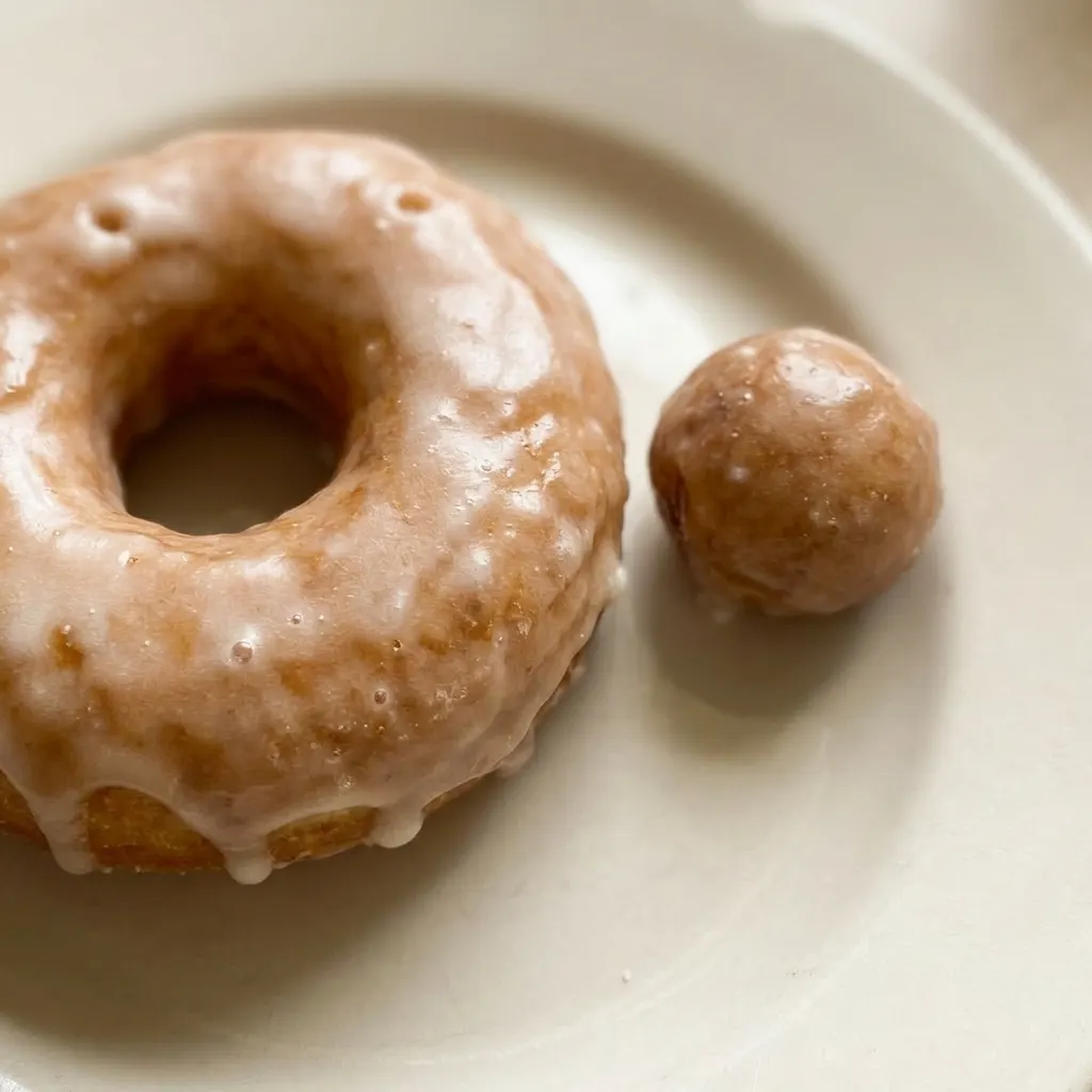 Zoomed in on a donut's golden-brown crust and thick white glaze with tiny flaxseed specks.