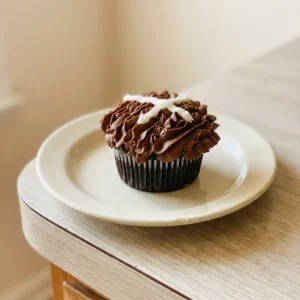 Top-down look at football-shaped cake made of chocolate cupcakes arranged in a grid, covered with chocolate buttercream and white buttercream stripes.