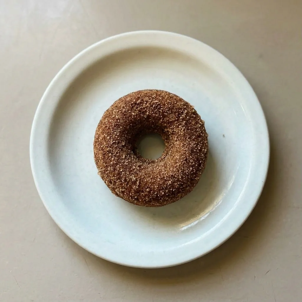 Ready to serve: two glazed donuts topped with cinnamon sugar, one cut in half revealing the almond flour crumb.