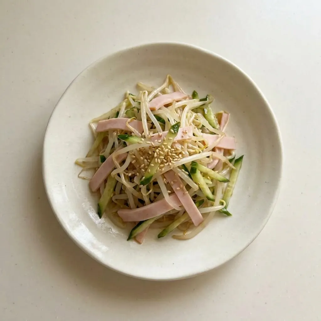 Ready to serve: a mound of bean sprouts with cucumber, ham, and sesame seeds, dressed in a soy sauce and sesame oil vinaigrette.