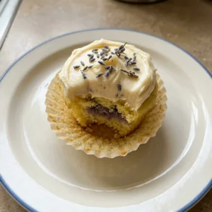 Bird's-eye view of a lavender honey cupcake with a swirl of honey buttercream and a sprinkle of dried lavender buds.