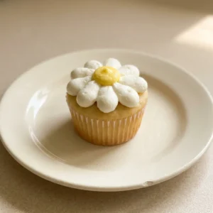 Bird's-eye view of a lemon cupcake topped with white daisy frosting and a dollop of lemon curd.