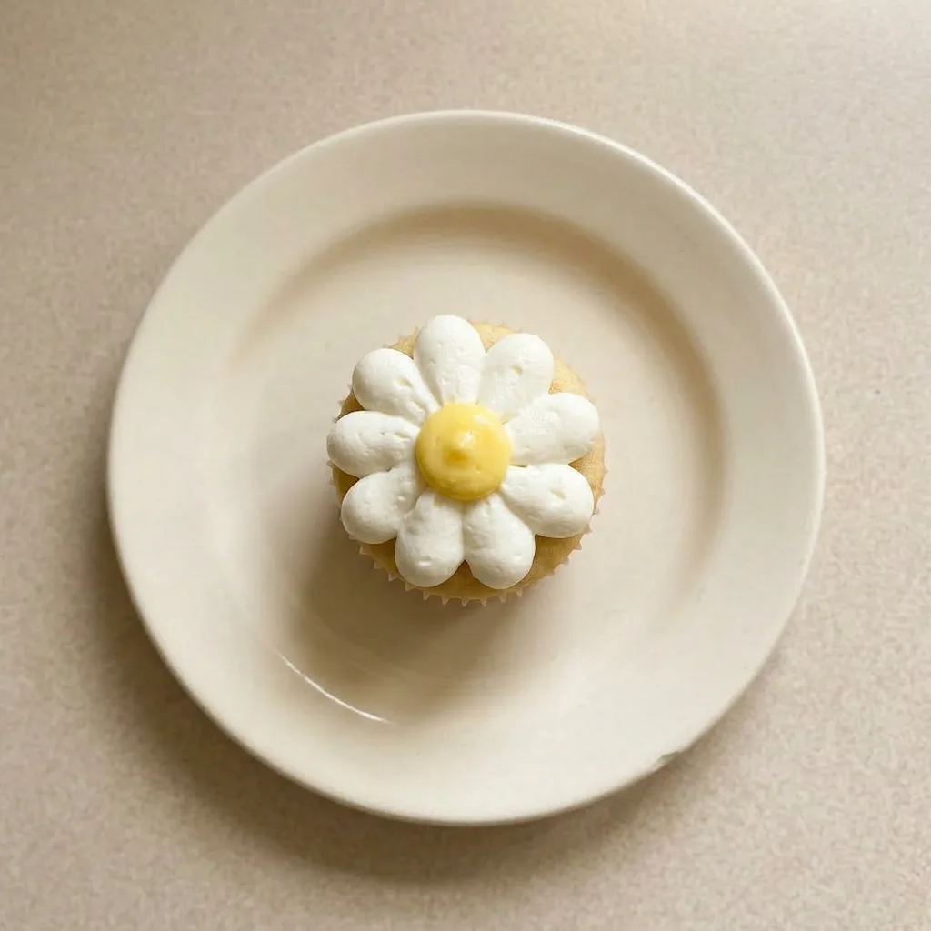Ready to serve: a lemon cupcake with white daisy frosting and a lemon curd topping.