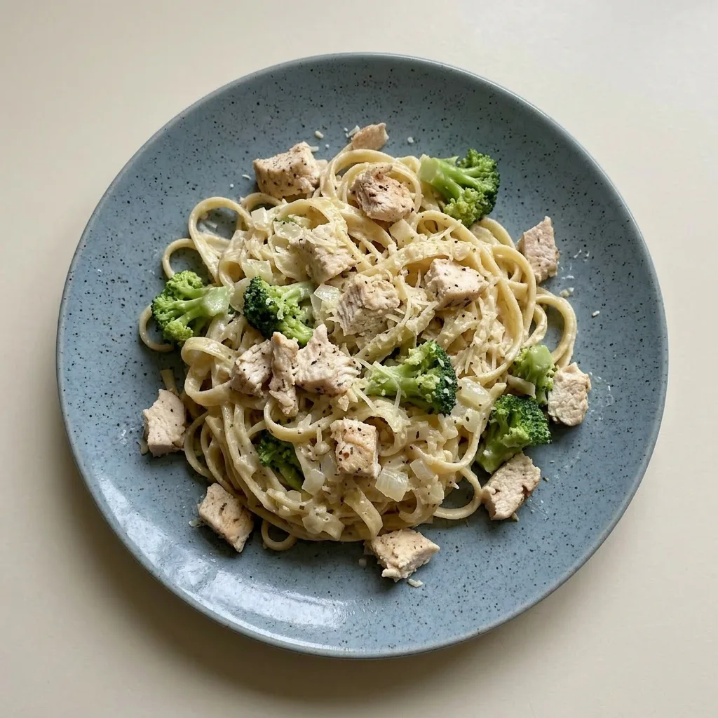 Ready to serve: pasta with chicken, broccoli, and creamy Alfredo sauce topped with Parmesan.