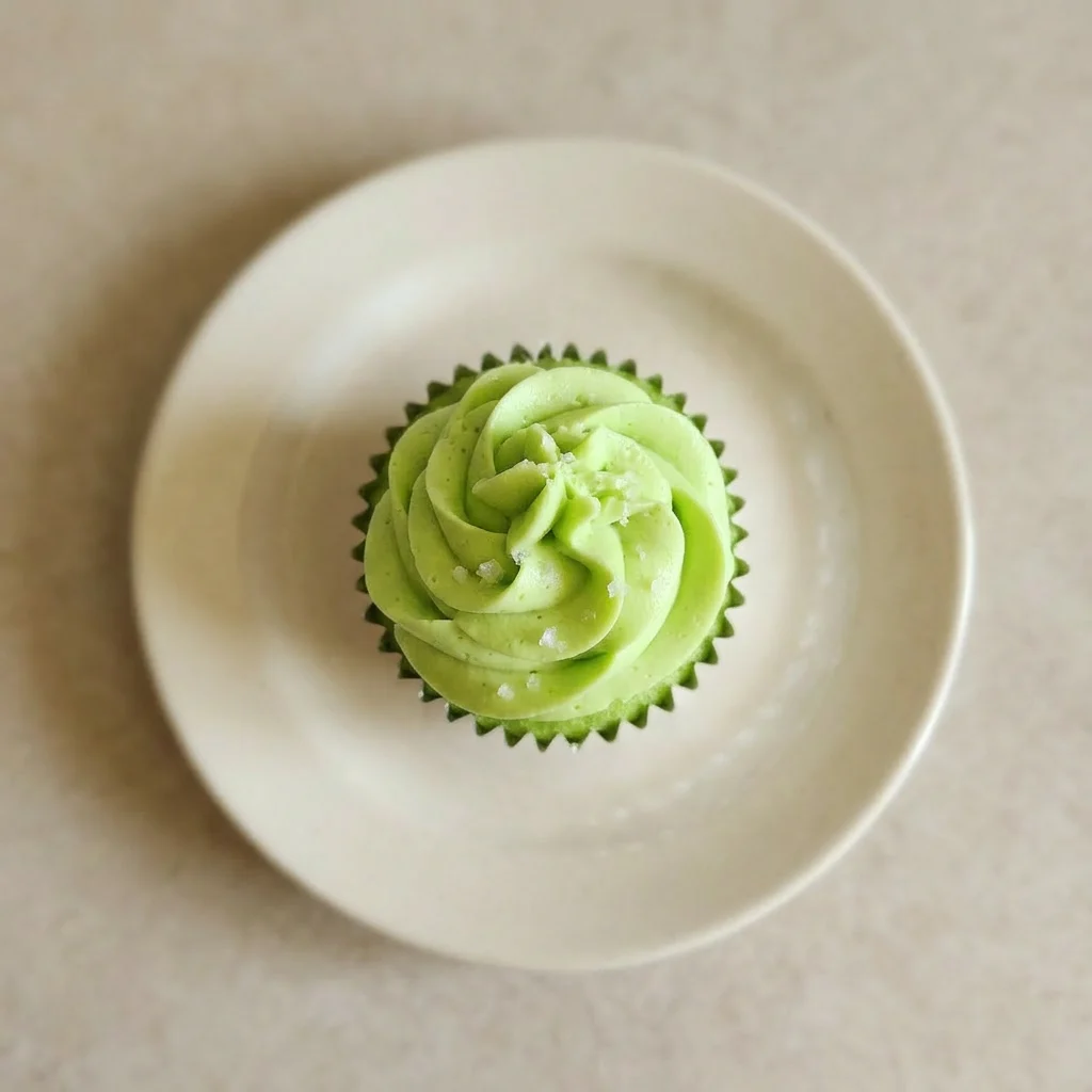 A plate of two margarita cupcakes garnished with lime wedges and a drizzle of tequila-lime syrup.