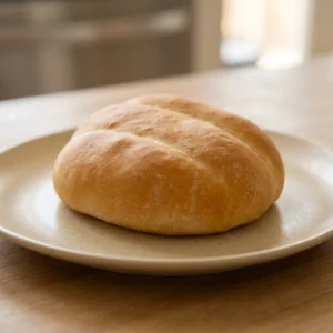 Top-down look at a round telera bread with a golden-brown crust and a light dusting of coarse salt.