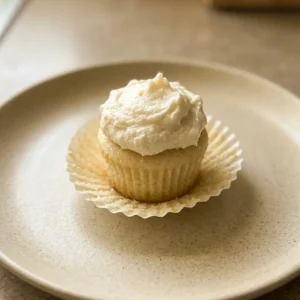 Bird's-eye view of mini cupcakes topped with swirls of white buttercream and a small dollop of whipped cream.