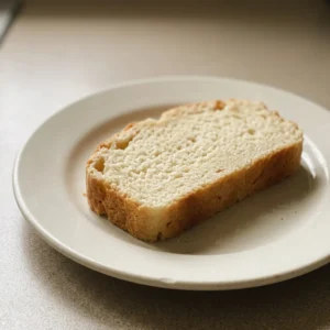 Overhead shot of a round loaf with a golden crust, sliced into wedges, drizzled with oil.