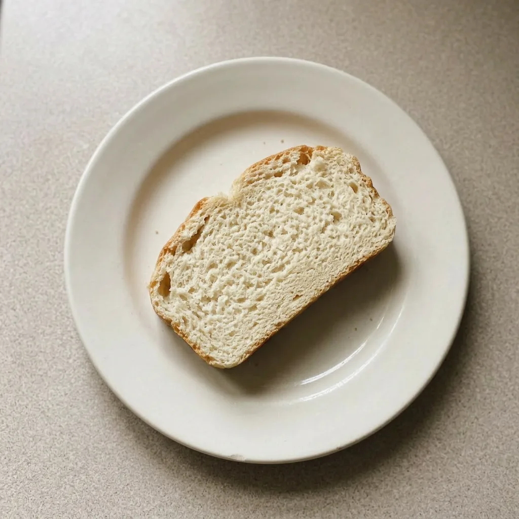 Plated bread slices on a dark surface, sprinkled with salt, beside a small bowl of olive oil.