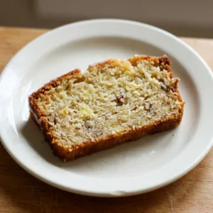 Looking down at a round pineapple bread with a golden-brown crust, topped with pineapple rings and a cherry in the center.