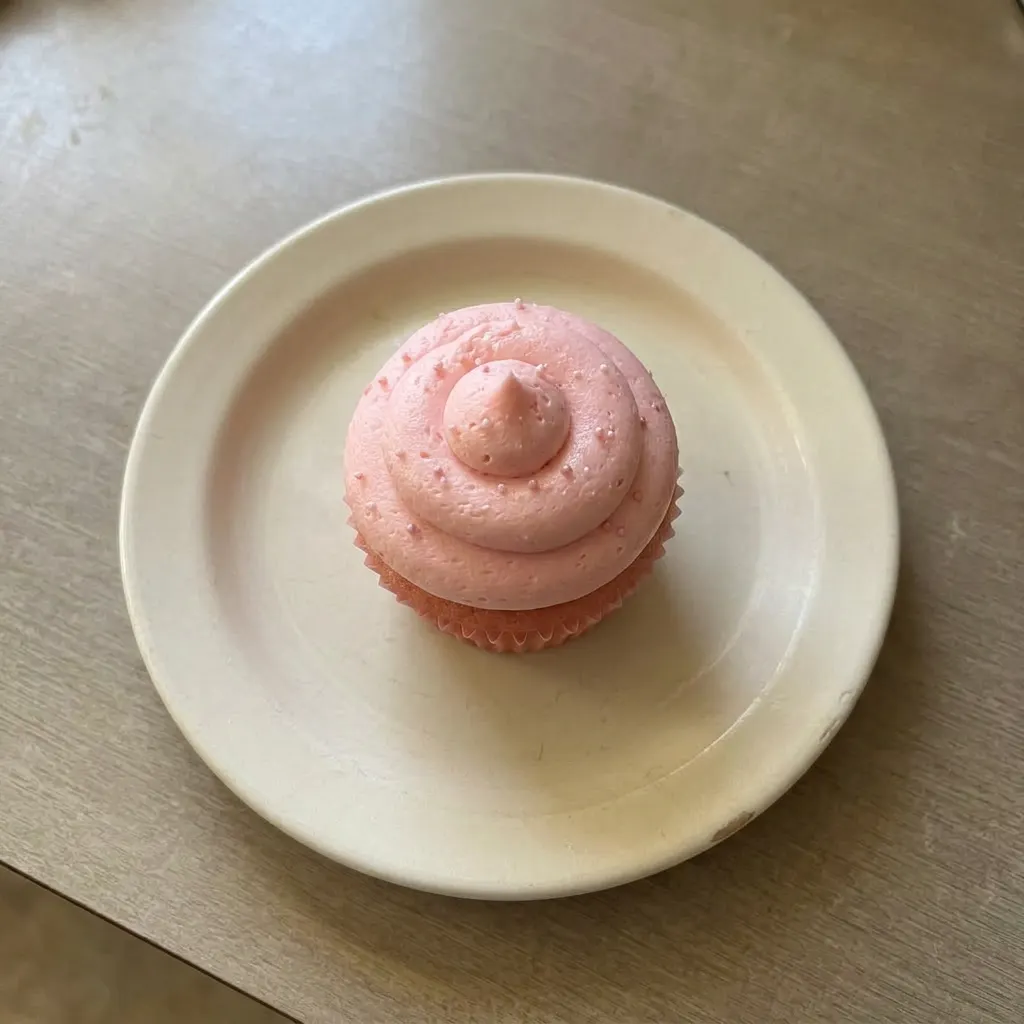 Plated pink velvet cupcake with cream cheese frosting, butter, and buttermilk visible in crumb.