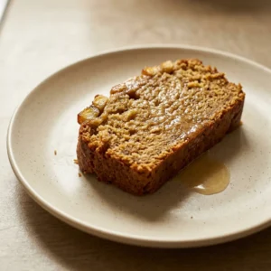 Top-down look at a round plantain bread slice with visible brown sugar crust and lime zest flecks.