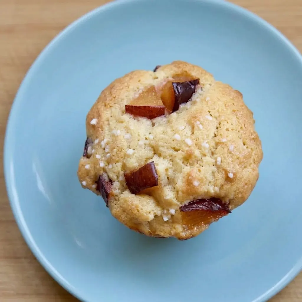 A serving of a plum muffin with a glossy plum slice on top and a tender, olive oil-enriched crumb.