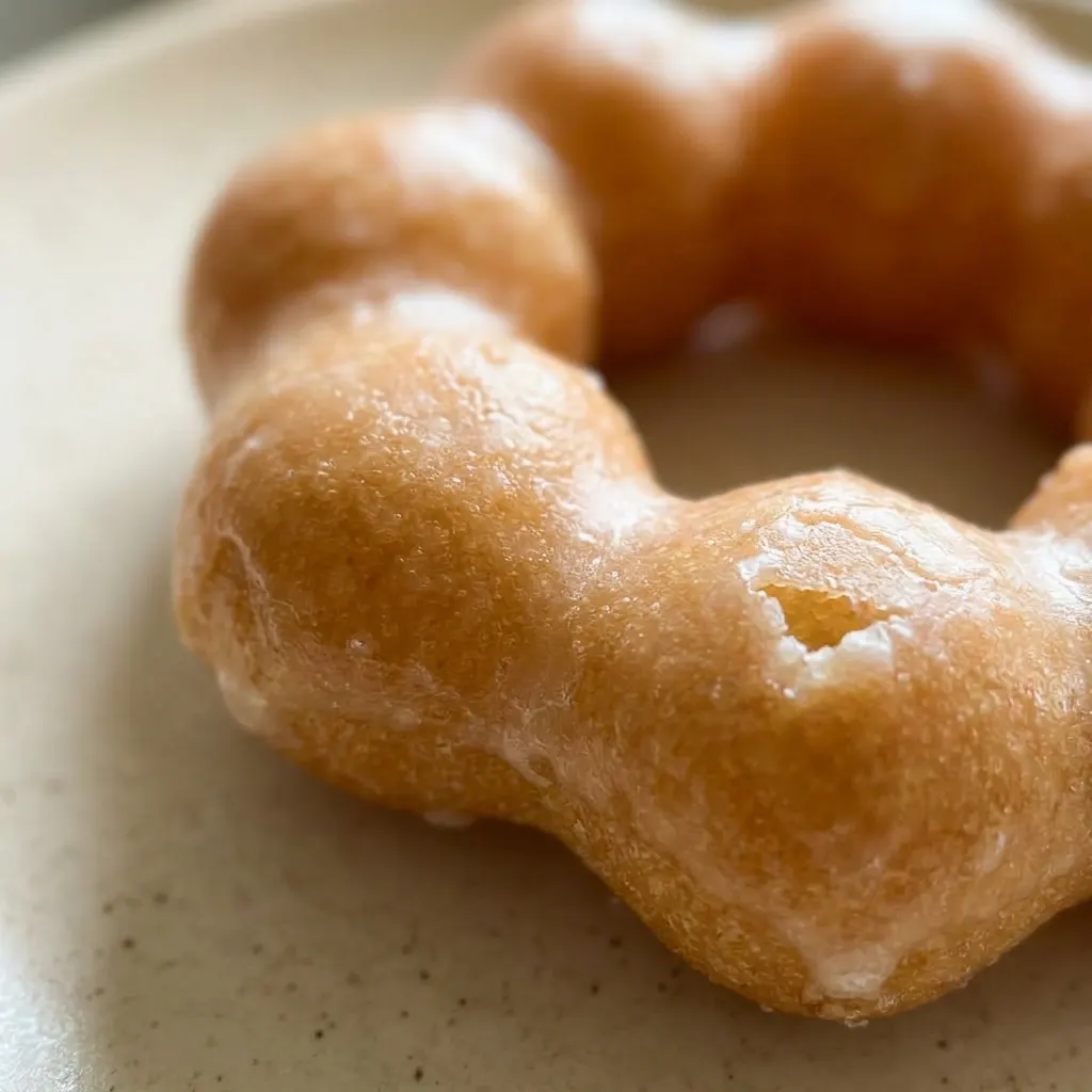 Macro detail of a matcha-glazed donut ring, showing green glaze pooling and fine tapioca flour specks.