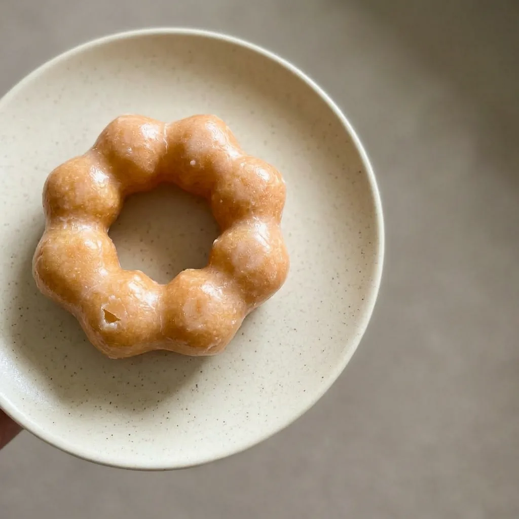 A serving of two matcha donuts stacked, glossy green glaze with visible tapioca flour.