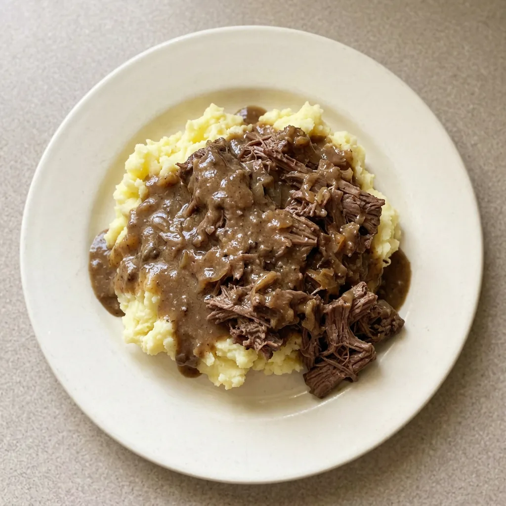A serving of two beef short ribs covered in a thick gravy with bits of mushroom and onion.
