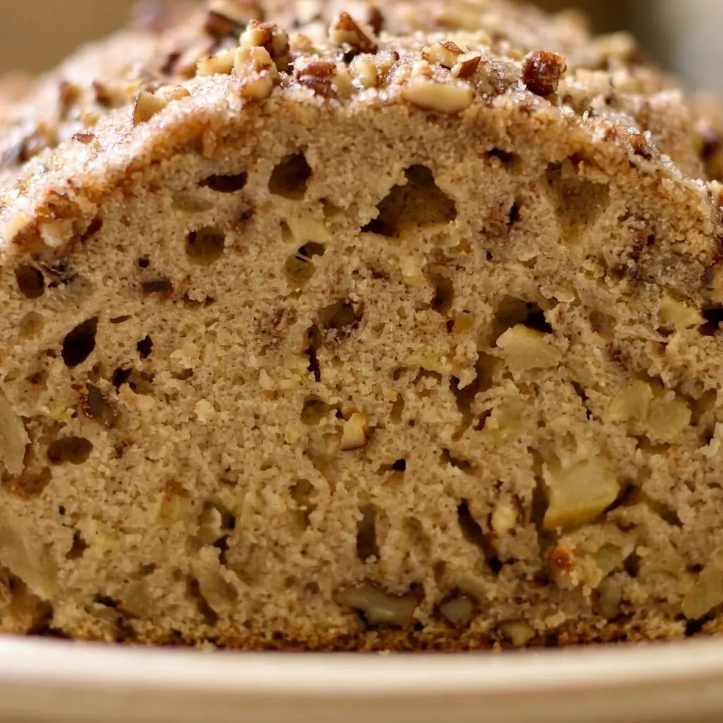 Macro detail of apple bread showing pecan pieces and cinnamon swirls in the crumb.