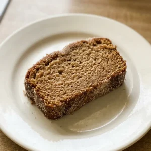 Top-down look at a round loaf cake with a cinnamon-sugar swirl on top, sliced into wedges.