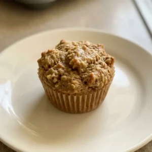 Overhead shot of a round apple cinnamon muffin topped with walnut pieces and cinnamon swirl on top.