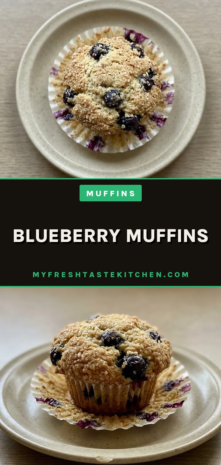 Overhead shot of a blueberry muffin with visible blueberries, a lemon slice, and crystallized ginger on top.