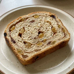 Overhead shot of a round loaf of cinnamon raisin bread with golden raisins and cinnamon swirl visible on the top crust.
