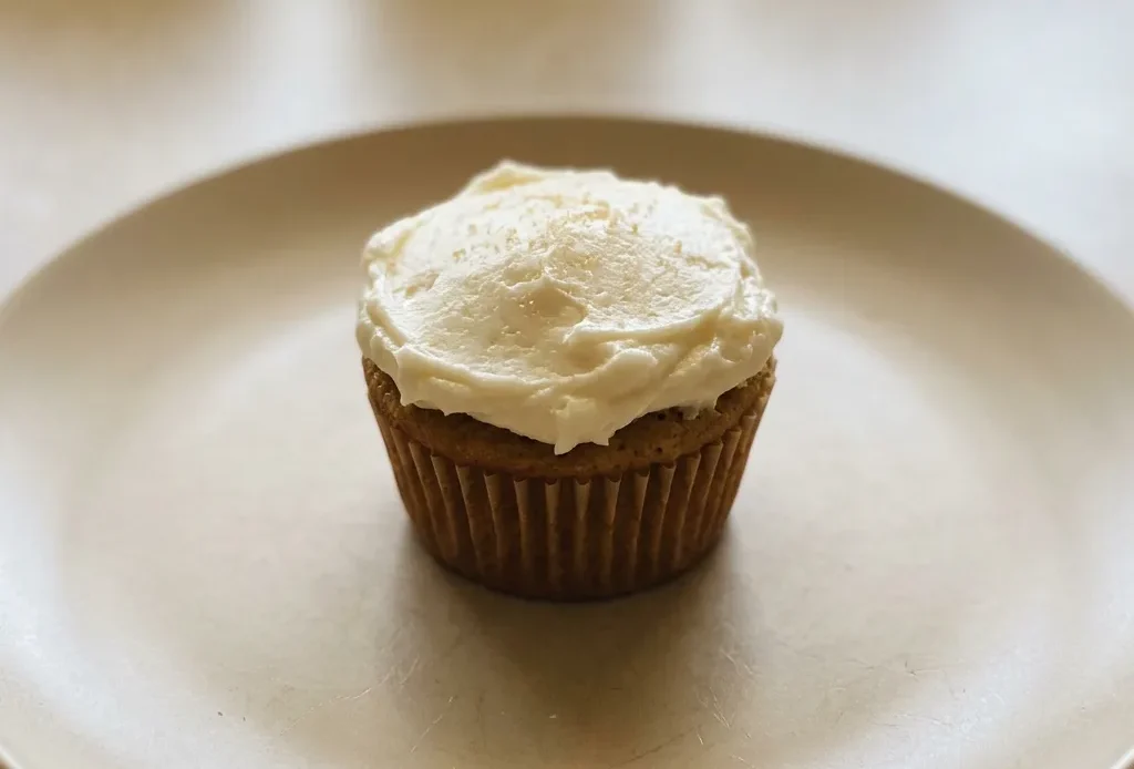 Bird's-eye view of a brown cupcake topped with swirls of white buttercream frosting.