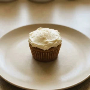 Bird's-eye view of a brown cupcake topped with swirls of white buttercream frosting.