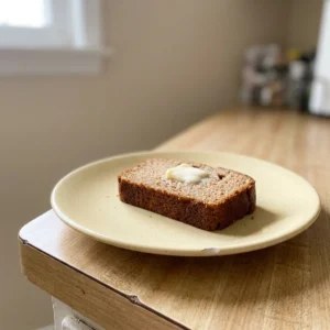 Top-down look at a slice of cinnamon applesauce bread topped with a dollop of Greek yogurt and a sprinkle of nutmeg.