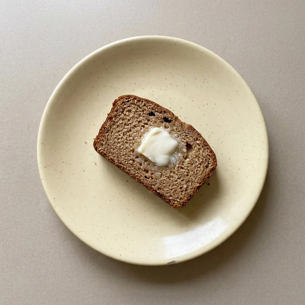 A serving of cinnamon applesauce bread, moist and dense, with a side of Greek yogurt and a dusting of nutmeg.