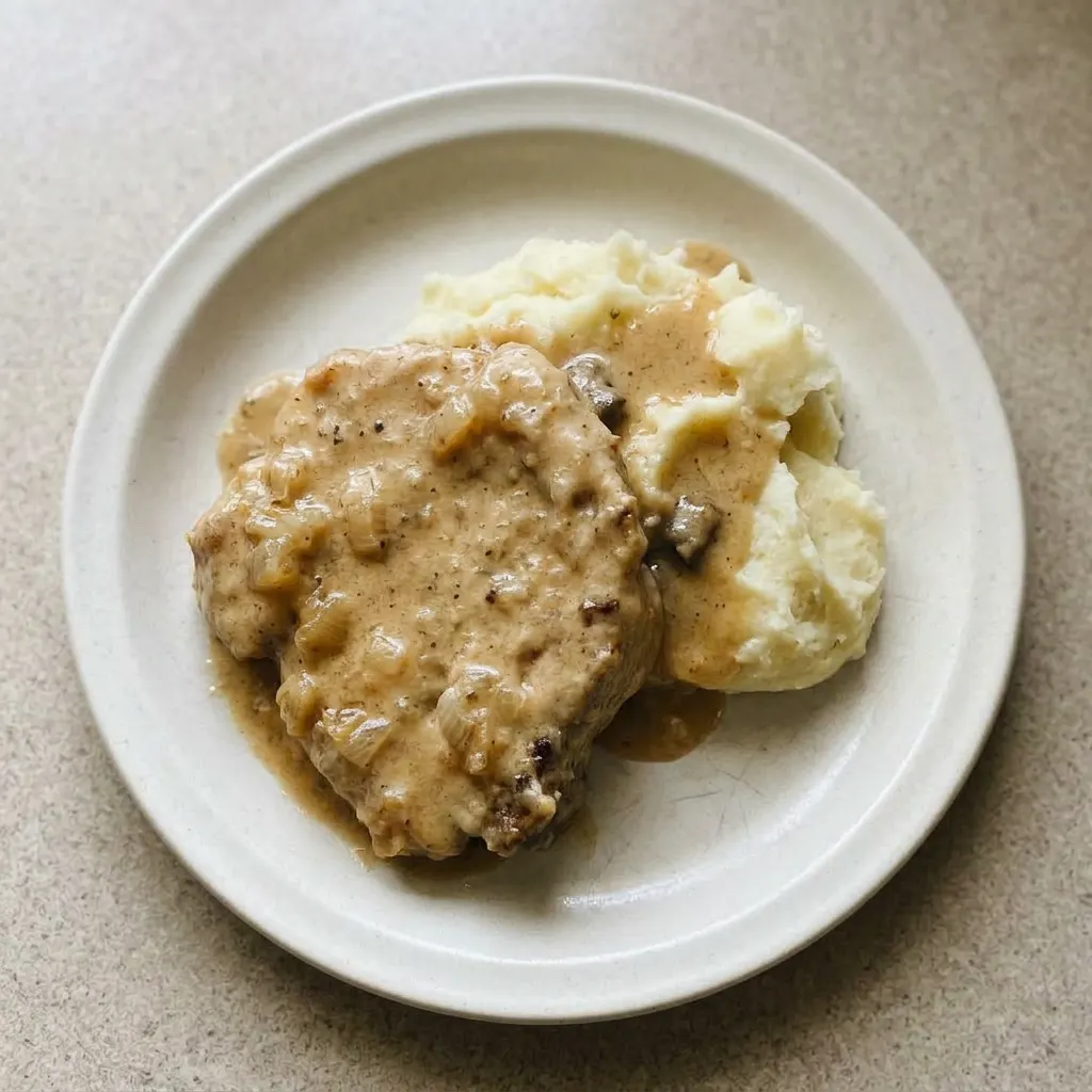 Ready to serve: a pork chop coated in savory gravy with caramelized onions.