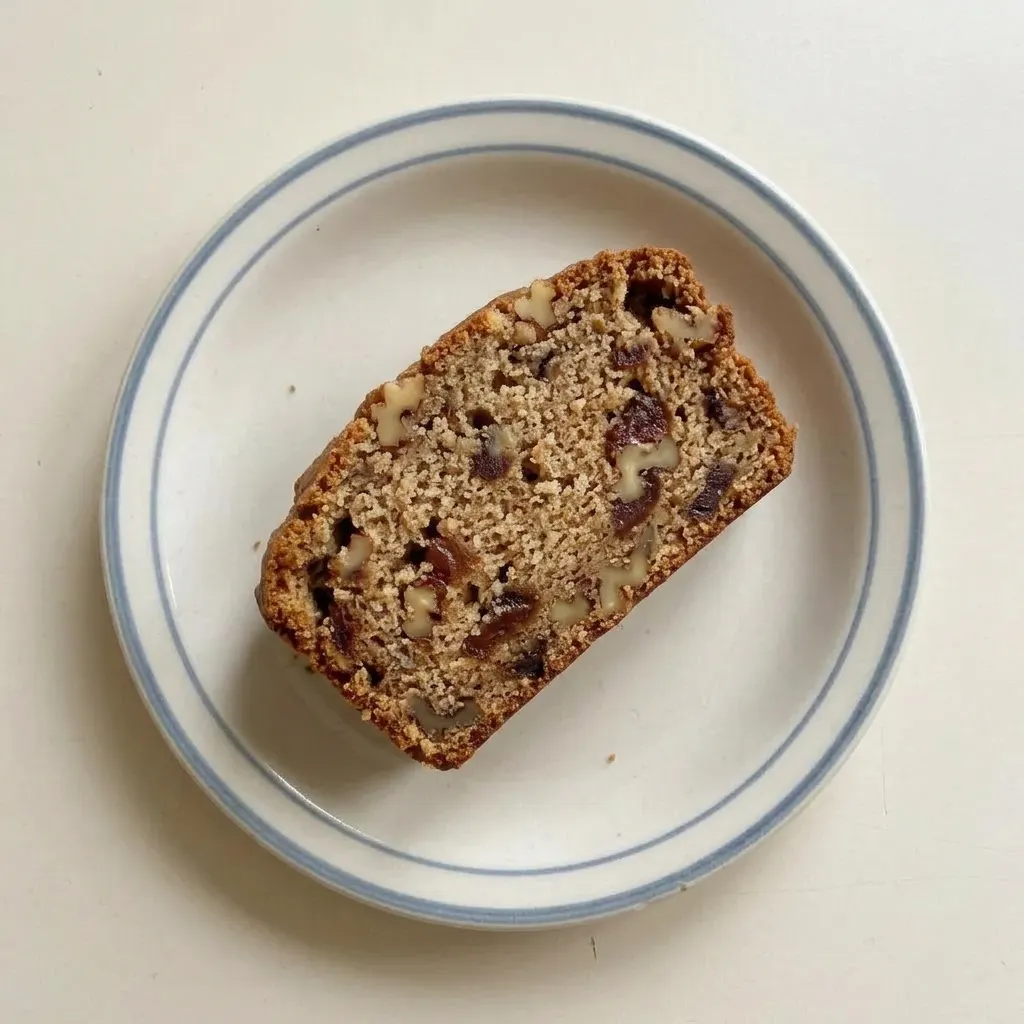 A plate of date nut bread slices, each with walnuts and dates, served with butter on top.
