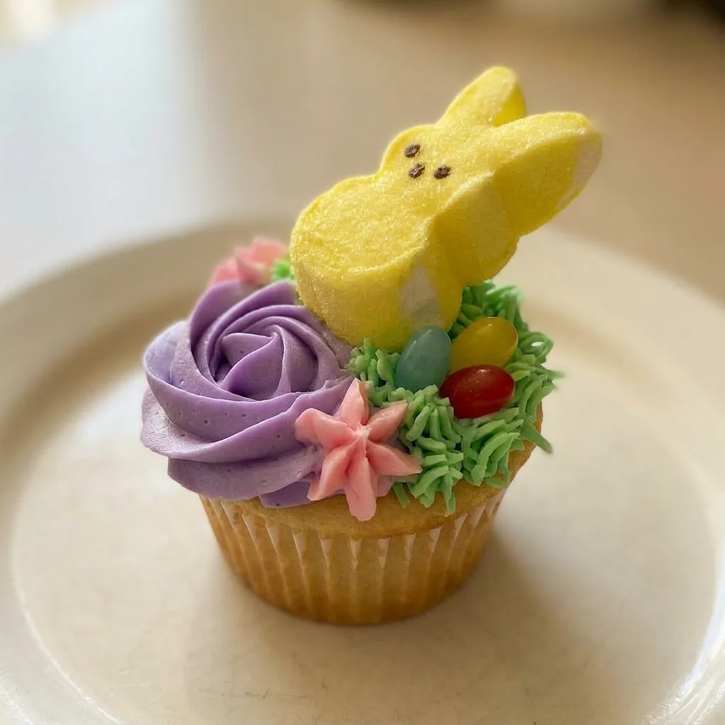 Up close, a cupcake with green frosting, jelly beans, and a yellow Marshmallow Bunny Peep.