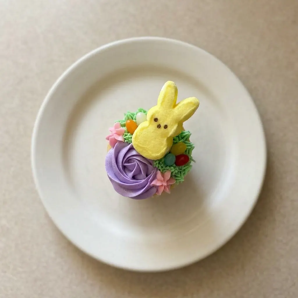 A plate of cupcakes with pink, purple, and green frosting, each decorated with jelly beans and a Marshmallow Bunny Peep.