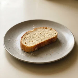 Overhead shot of a round loaf of bread with a golden crust, drizzled with olive oil and sprinkled with flour.
