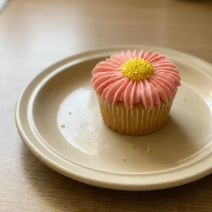 Top-down look at three flower-shaped cupcakes with pink, yellow, and purple buttercream petals and white centers.