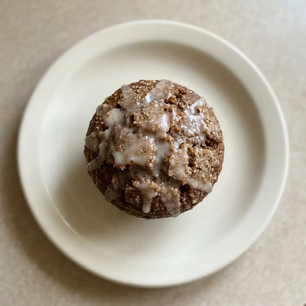 Plated glazed gingerbread muffin with a glossy icing, cinnamon and nutmeg visible on top.
