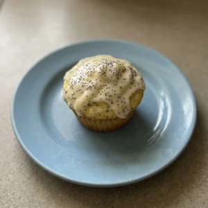 Overhead shot of a lemon poppy seed muffin topped with powdered sugar, showing a golden-brown dome with visible poppy seeds.