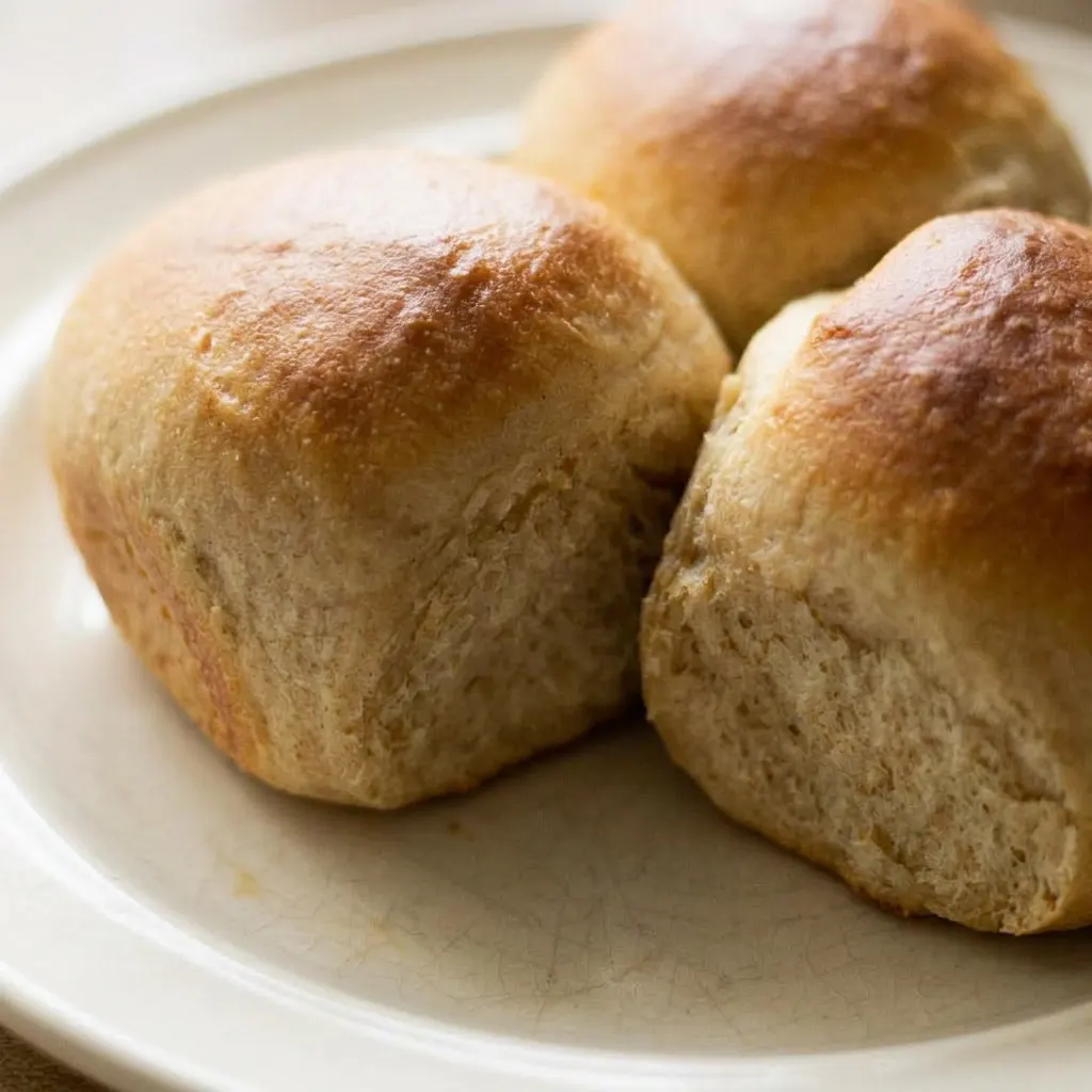 Up close, a warm dinner roll with a soft, fluffy interior and a glossy, honey-brushed top.