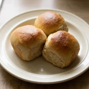 Looking down at six golden-brown dinner rolls arranged in a circle, each topped with a light honey glaze.