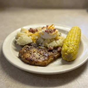 Bird's-eye view of two pork chops seasoned with dark speckles and red paprika, arranged side by side.