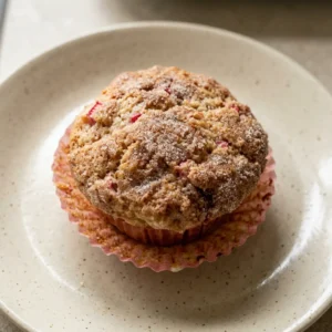 Looking down at two rhubarb muffins with Greek yogurt dollops and cinnamon swirls on top.